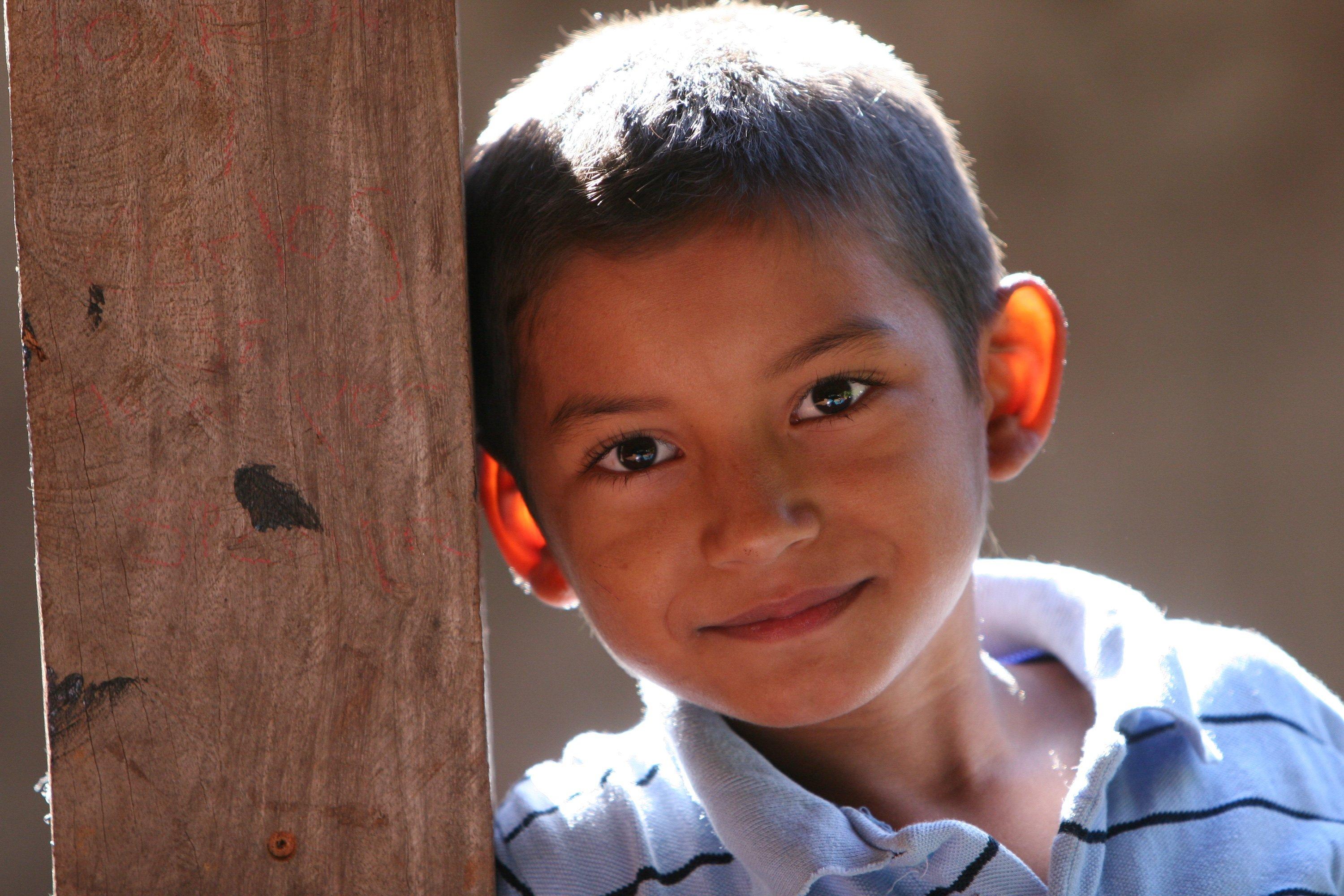 A boy with a placid smile, sunlight shining through his ears from behind. 